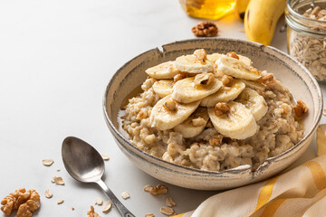 Bowl of oatmeal porridge with banana, honey and walnuts. Healthy diet breakfast