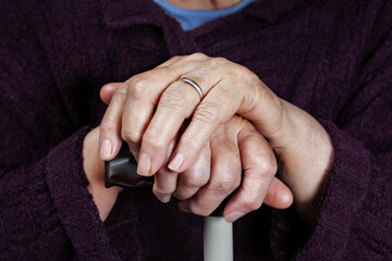 Hands of an elderly woman on a cane