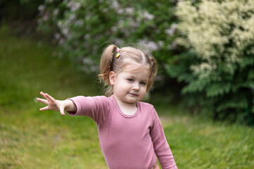 toddler girl stretches her hand out for something, children curiosity, outdoor fun - obrazy, fototapety, plakaty