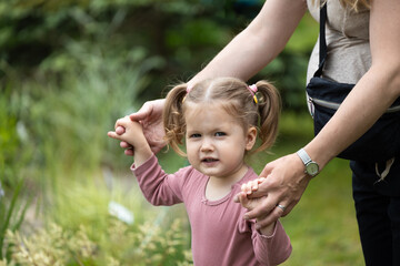 toddler girl is hold by mother hands, children activity outdoor, care of mother - obrazy, fototapety, plakaty