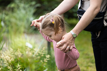 toddler girl is hold by mother hands, children activity outdoor, care of mother - obrazy, fototapety, plakaty