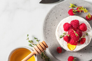 Camembert cheese with fresh berries, honey and thyme on white background. Healthy snack. French appetizer. Top view