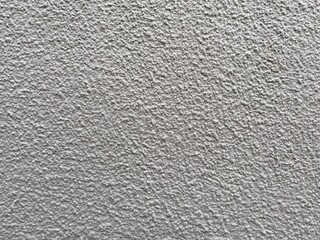 Roughcast surface. Grunge texture as background. Bumpy gray exterior wall with small frequent cracks. Rugged coarse cement or concrete rendering. Painted pebble dash. Uneven structural plaster finish.