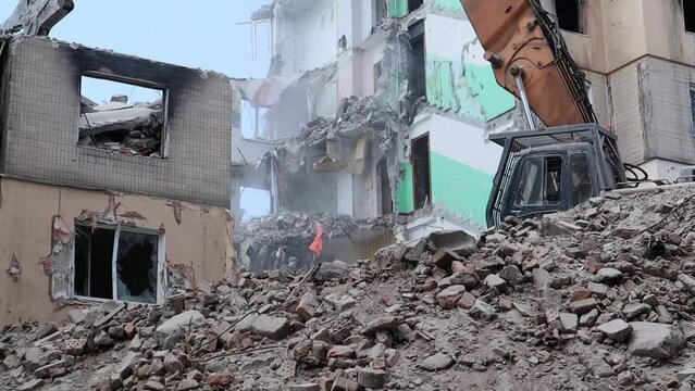 Excavator with hydraulic crusher at the demolition of a residential building. City renewal. Dismantling, destruction of a high-rise multi-storey building for reconstruction. Debris clearing.