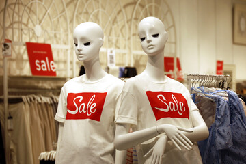 T-shirts with Sale inscription on mannequins in clothing store. Different summer clothes for men...