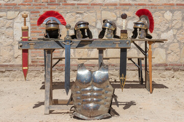 outdoor display of helmets, swords and cuirass of soldiers from the ancient roman empire