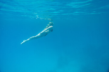 Woman swimming in open sea. Close up underwater photo. Diving girl in open water.