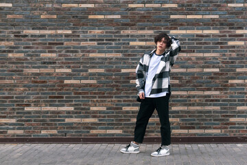 young man posing against a brick wall
