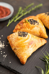 Homemade asian pastry samosa on black. side view, selective focus.