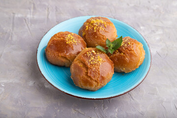 Traditional turkish dessert sekerpare with almonds and honey on gray concrete, side view.