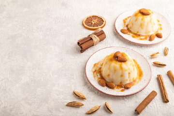 White milk jelly with caramel sauce on gray concrete, side view, copy space.