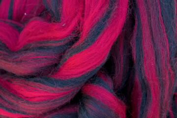 Multicolored red blue strings of wool for felting and spinning as a background.
