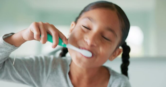 Face, girl and brushing teeth with wellness, oral hygiene and cleaning in a bathroom, growth or care. Portrait, female child or kid with dental health, home or toothpaste with fresh breath or routine