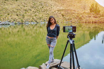 latina woman on vacation taking a cell phone video of herself with a lake in the background in la paz bolivia