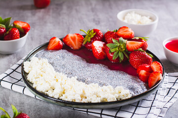 Breakfast plate of cottage cheese, chia pudding, jam and strawberries on the table