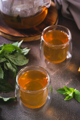 Calming green mint tea in cups and teapot on the table vertical view
