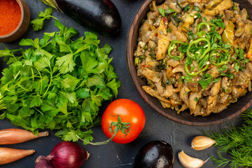 Above view of yummy eggplant dish fresh vegetables green bundle pepper on dark color table