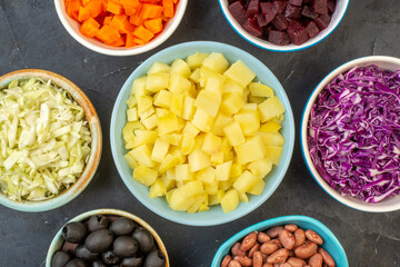 Close up view of set of chopped fresh foods in bowls on dark color background