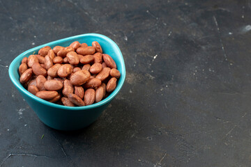 Front view of brown beans in a blue bowl on the right side on dark color background with free space