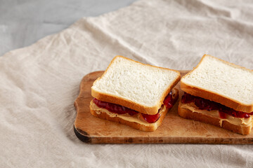 Homemade Peanut Butter and Jelly Sandwich on a rustic wooden board, side view.