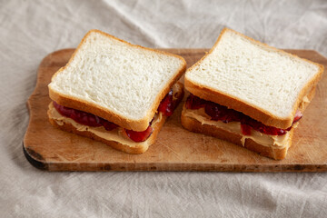 Homemade Peanut Butter and Jelly Sandwich on a rustic wooden board, side view.