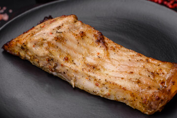 Slice of delicious baked fish with salt, spices and herbs on a ceramic plate