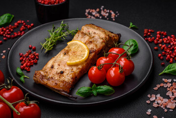 Slice of delicious baked fish with salt, spices and herbs on a ceramic plate