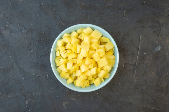 Horizontal view of chopped boiled potatoes in a bowl on dark color table with free space