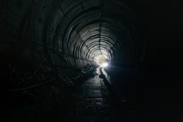 Dark dirty abandoned subway tunnel with rusty railway