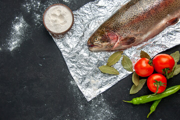 Horizontal view of scales removed fresh fish vegetables flour in a bowl on dark color background