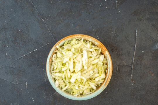 Horizontal view of white cabbages in a bowl on dark color background with free space