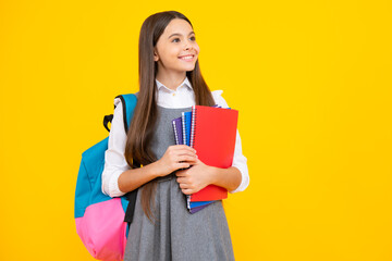School girl hold copybook and book on yellow isolated studio background. School and education concept. Teenager girl in school uniform.