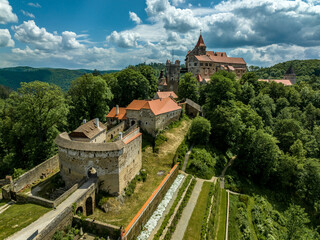 Fototapeta na wymiar Aerial view of Pernstejn castle with Gothic palace red roof, rectangular and round towers, barbican, forward gun platform in Moravia