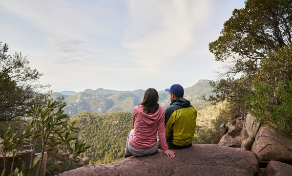 Unrecognizable couple sitting on mountain