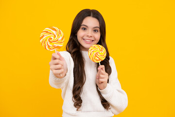 Teen girl hold lollipop caramel on yellow background, candy shop. Teenager with sweets suckers. Happy face, positive and smiling emotions of teenager girl.