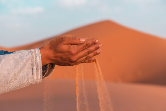 Sand falling from the hands of crop person in desert