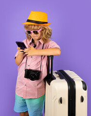 Child traveler with suitcase isolated on studio background. Tourist kid boy. Portrait of child travel with travel bag. Travel, adventure, vacation.