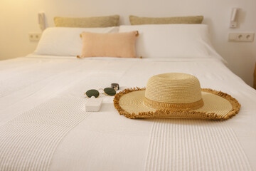 Straw hat and sunglasses on bed