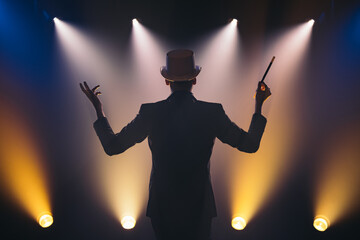 Man with magic wand on stage in spotlight