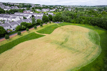 Aerial view on a green grass field with freshly cut field with strange shapes. Nature background. Design in forest park.