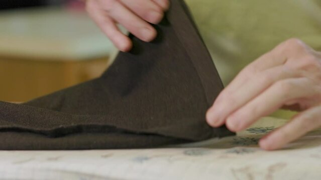 tailor creasing the new hem line for the pants leg