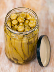 Closeup of pickled okra in a glass jar on a table in a restaurant, vegetarian food