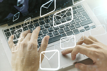 Double exposure of postal envelopes hologram with hands typing on laptop on background. Electronic...