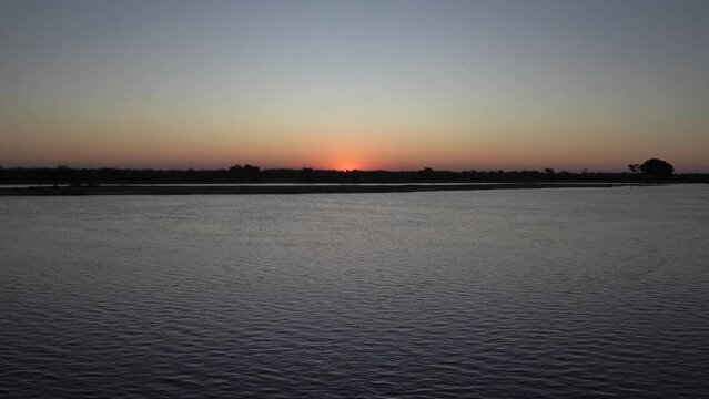 Panorama view of the river and sun hiding in the horizon at sunset.	