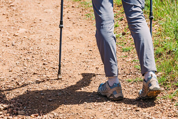 Close-up of feminine feet hiking on the trail with hiking poles