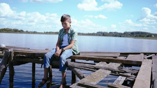 Solitude by the Lake: Sad Boy Contemplating Life on the Pier Amidst Sunny Weather