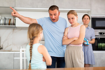 Family scene in kitchen, unpleasant conversation Parents stand face to face with daughter and scold...
