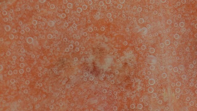 Close-up of watermelon slice in liquid with bubbles. Ripe watermelon in water. Close-up of red melon slice covered by bubbles. Macro horizontal image.