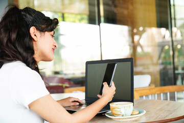 Businesswoman using laptop and mobile phone logging in online banking