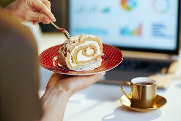 Closeup on modern woman with laptop and piece of cake